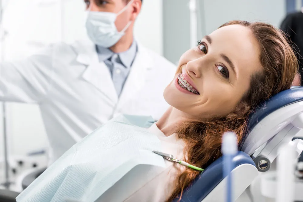 Adolescent patient smiling on the dental chair after receiving braces in Boca Raton. 