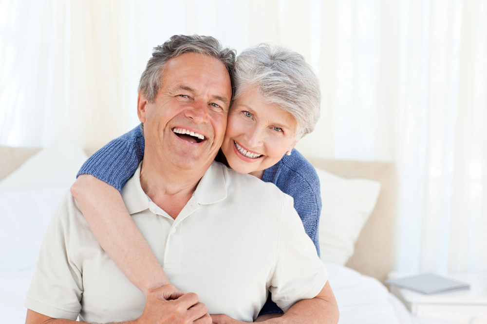 Elderly couple smiling after receiving dental implants in Boca Raton. 