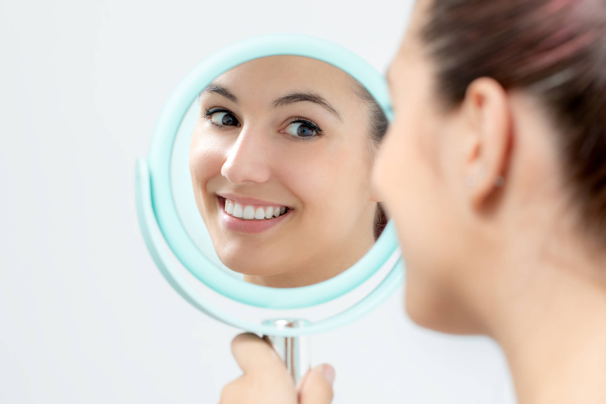 woman checking out her smile after visiting a Cosmetic Dentist Boca Raton